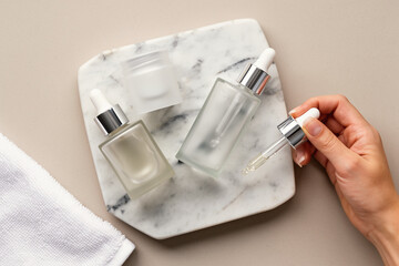 Skincare bottles and dropper on marble flatlay.