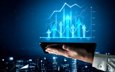 A hand holds a tablet displaying dynamic graphs and data visuals symbolizing growth and financial...