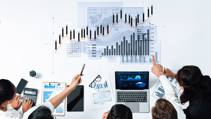 A diverse team collaborates over financial charts and data on a table, discussing strategies and insights for improving business performance and growth. Scalp