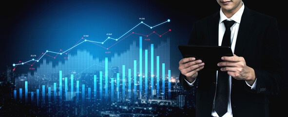 A businessman in a formal suit analyzes data on a tablet amid glowing graphic charts representing financial indicators, symbolizing modern data-driven decision-making. Scalp