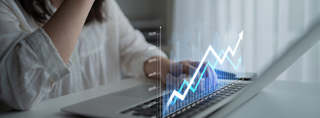 A business professional engages in financial analysis on a sleek laptop, showcasing growth indicators and data visualization in a contemporary office environment. Scalp