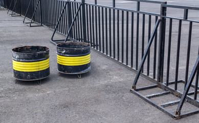 DIY Metal Drum Trash Bin with Black Iron Fence on Asphalt