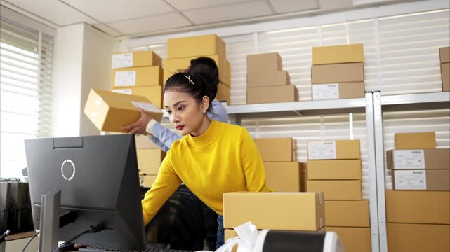 Business owner and employee labeling packages using printer and tablet in warehouse office
