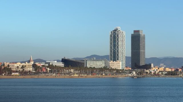 Wide panoramic view of Barcelona coastline skyline with modern buildings and calm Mediterranean sea, clear blue sky and urban beach cityscape, travel destination background with copy space