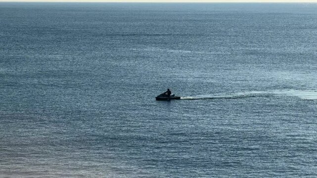 Jet ski riding across the Mediterranean sea with wide open water, dynamic travel video showing freedom and motion, personal watercraft on blue ocean with copy space and minimal composition