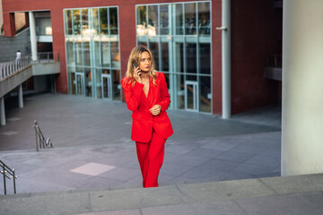 Businesswoman in Red Suit Talking on Phone While Walking Down Stairs Outside Office Building