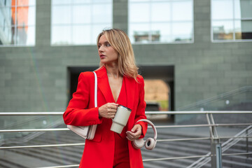 Businesswoman commuting to office holding coffee and headphones