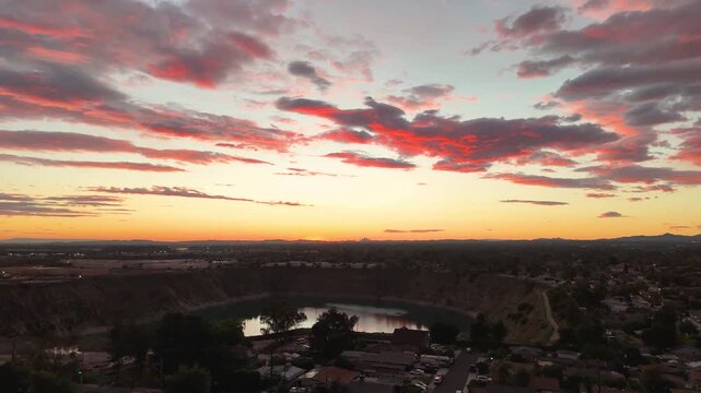 Aerial footage of a lake surrounded by homes and lush green trees at sunset in Duarte California USA