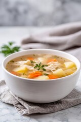 Steaming chicken soup in a white bowl, offering a comforting and healthy meal with shredded chicken, carrots, and potatoes