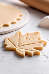 Maple leaf cookie dough cut out with decorative veins, preparing fall holiday sugar cookies for baking