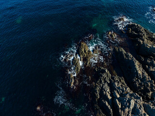 Waves crashing against rugged rocks at dawn creating a serene coastal scene with vibrant blue waters