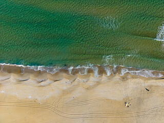 Tranquil shoreline at sunset with gentle waves lapping against warm golden sand on a serene beach location