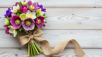 Bouquet of colorful flowers tied with burlap ribbon on wooden background