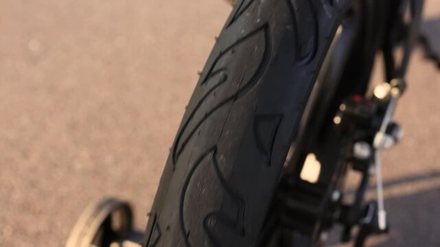 Close up of rotating rear wheel tire on small child bicycle showing detailed tread pattern in bright sunny weather capturing joyful motion safety and outdoor riding concept