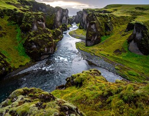 Deep canyon landscape with a winding river and lush green vegetation on the sides, under a cloudy sky