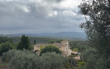 Fototapeta premium Charming villa on hillside surrounded by nature, trees, and scenic mountain views.