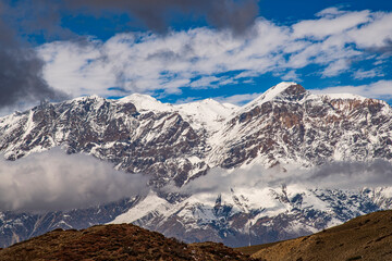 Snow-covered Nilgiri mountains under moving clouds near Muktinath, Nepal. Expansive Himalayan alpine scenery with dramatic weather, rugged ridgelines, and high-altitude terrain in the Annapurna region © Augusto