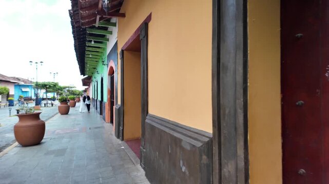 Exploring the streets of Granada Nicaragua filled with colonial architecture, local shops, and people walking by during the day.
