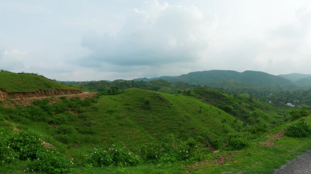 4K shot of green hills of Sahyadri range as seen from moving vehicle. Rayta hills during monsoon season. Lush green forest of Sahyadri hills and clouds in sky. Nature landscape.