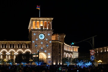 Fototapeta premium Government Building of Armenia on Republic Square in Yerevan, decorated with Christmas lights and clock, captured at night with low light grain.