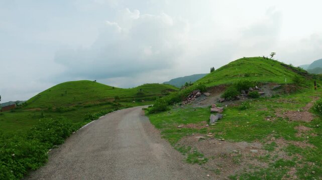 4K Wide angle view of road passing through green Sahyadri Hills at Rayta village in Udaipur, Rajasthan, India. Nature landscape. Monsoon clouds above green hills. Travel background.