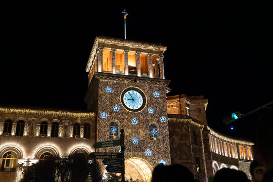 Government Building of Armenia on Republic Square in Yerevan, decorated with Christmas lights and clock, captured at night with low light grain.