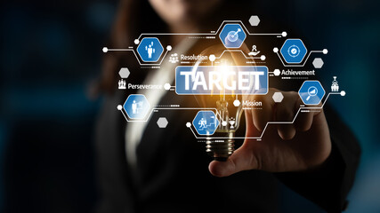A business professional emphasizes the concept of target achievement using a light bulb and graphic icons representing mission, resolution, and perseverance in a dynamic environment. Tessel