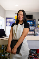 Woman entrepreneur wearing an apron, happily working in her retail store