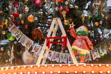 Moscow, Russia, 29 December 2025 Close-up of a decorated Christmas tree with postcards garland, ornaments, lights, a wooden ladder, and a holiday figurine holding a star.