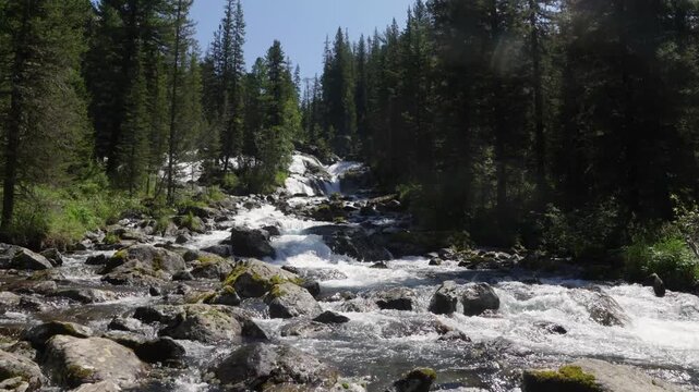A large waterfall in the Altai Mountains, falling into the valley from high cliffs