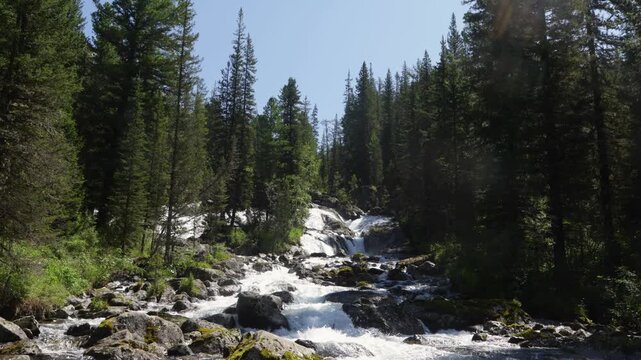 A large waterfall in the Altai Mountains, falling into the valley from high cliffs