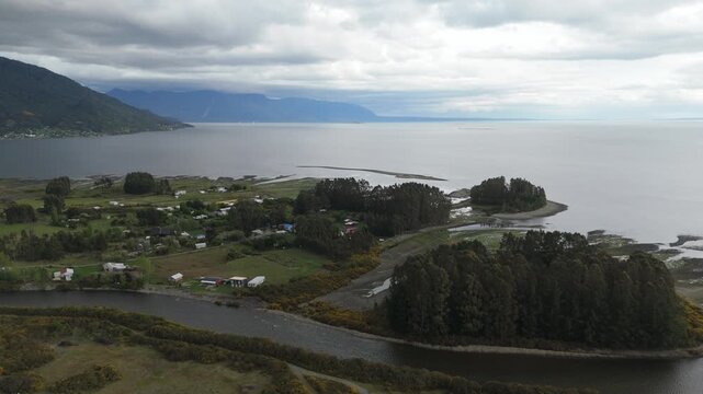 Aerial Spiral View of Island Separated by River with Mirror Reflections and Heavy Clouds