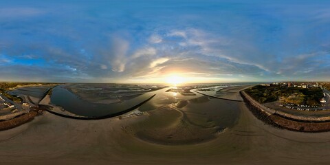 Ultra-wide 360 drone panorama of Authie Bay estuary at Berck, France during golden sunset, showing sandbanks, tidal channels and jetty under dramatic cloudscape
