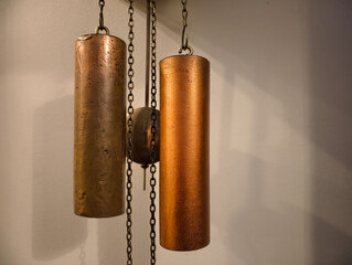 Vintage cylindrical copper and brass clock weights suspended on chains and a pendulum from an...