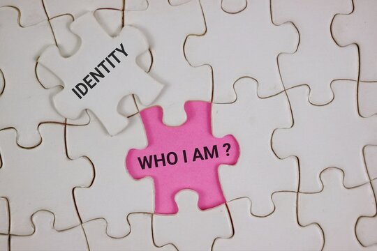 A pink puzzle piece reading 'Who I Am?' sits among white pieces labeled 'Identity,' symbolizing self-discovery and personal identity. Ideal for psychology, branding, and introspection themes.