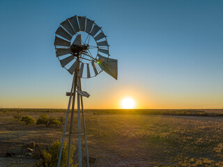 Metal Windmill In Grassy Field with Orange and Blue Sunset Sky