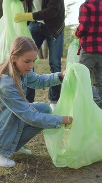 Protection of environment concept where pleasant active diverse young people and children - nature lovers collecting different waste into plastic packs from park territory