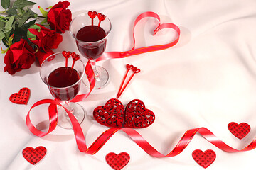 Two glasses of red wine on a festive table with roses, hearts, and a ribbon. Valentine's Day concept, advertising for a bar and cafe. Banner for an invitation to a festive buffet, card for a wedding,