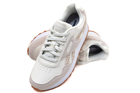 White and beige Reebok sneakers with leopard print details on white background studio closeup