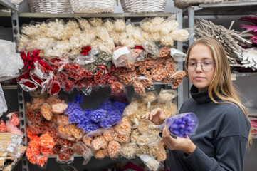 A Caucasian woman buys dried flowers at a home decor store.