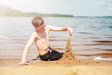 Young Boy Building Sand Castle by the Lake