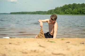 Child enjoying a sunny day by constructing a sandcastle on the beach. The youngster's focus and creativity are visible as they mold the sand, capturing a joyful childhood moment