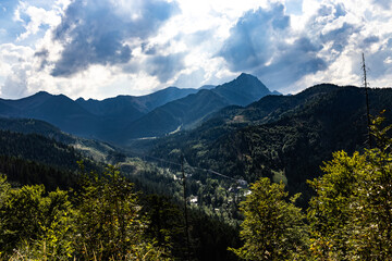 Mountain valley landscape in Tatra Mountains with forested slopes and dramatic clouds over ridgelines