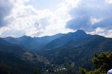 Wide mountain panorama with layered ridges and sunlight breaking through clouds in Tatra Mountains