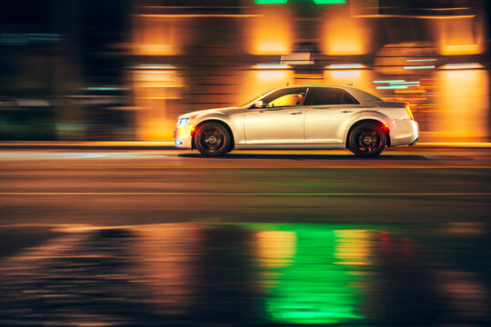 LOS ANGELES, CA - October 24,. 2025: Fast moving Chrysler 300 sedan car driving on illuminated night city road. Blurred motion