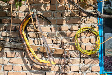 Handsaw, chainsaw, cables hanging on the wall. Agricultural tools.