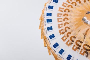 Fanned out fifty euro banknotes arranged in a circular pattern on a clean white surface, showcasing...
