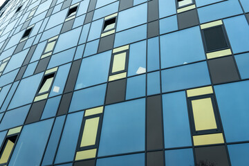 Modern building facade with blue and yellow glass windows in geometric grid pattern. Abstract urban...