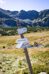 Trail signpost in Valley of Five Polish Ponds, Tatra Mountains with mountain ridges in the background