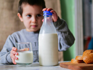 Young Boy Closing a Glass Milk Bottle after Pouring a Glass at Breakfast